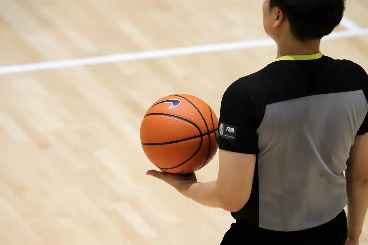 Dommer med basketball på indendørs bane